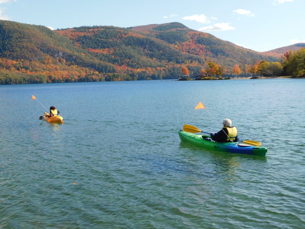 man and boy in kayaks on sun-drenched lake in the fall